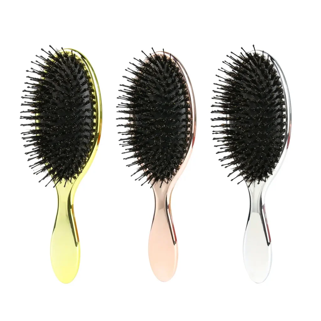 Three oval hair brushes in gold, rose gold and silver finishes